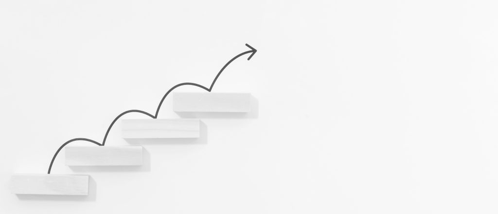 Stepped blocks with an arrow pointing upwards, symbolizing strategic scaling and growth in business.